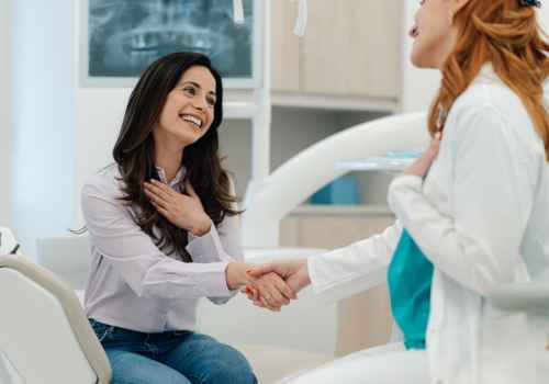 Young woman in dental office, shaking dentist's hand and smiling
